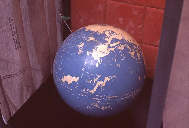 Mneme XVII: There's No Place Like Home: detail: bowling ball earth with flag