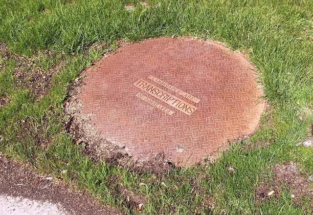 Mneme XXXI: Dwelling in the Plan: exterior: false manhole (cast iron) with text: “Landscapes are transcriptions of ourselves” (Relph)