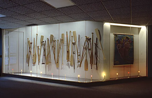 Surveying Desire X: Quest: display case with crutches, paddles, map, electric candles, and paired texts