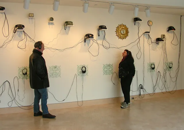 Surveying Desire XV: Overtures: wall section with telephones, clocks, and headphones