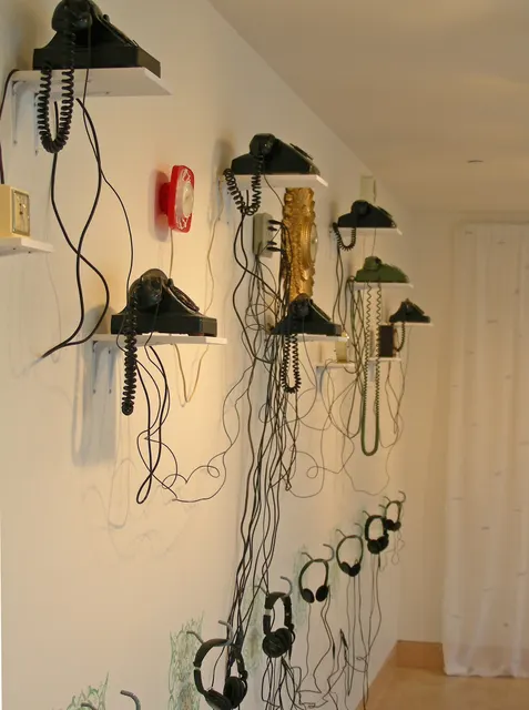 Surveying Desire XV: Overtures: wall section detail with telephones, clocks, and headphones
